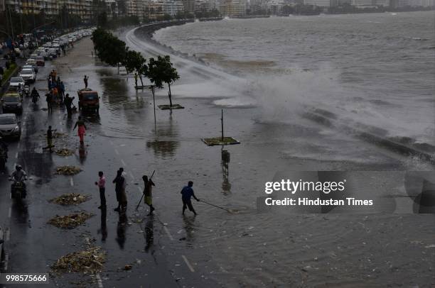Workers clean the promenade of Marine Drive after High Tide, on July 13, 2018 in Mumbai, India. The BMC has also listed 24 high tide days, of which...