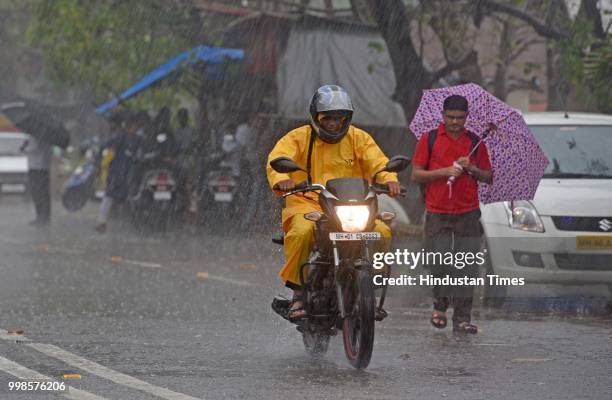 People deals with heavy rain at Bandstand, Bandra, on July 13, 2018 in Mumbai, India. Heavy rains made a comeback in Mumbai causing waterlogging in...