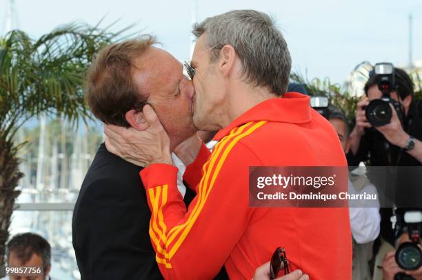 Director Xavier Beauvois receives a kiss from actor Lambert Wilson during the 'Of Gods and Men' Photo Call held at the Palais des Festivals during...