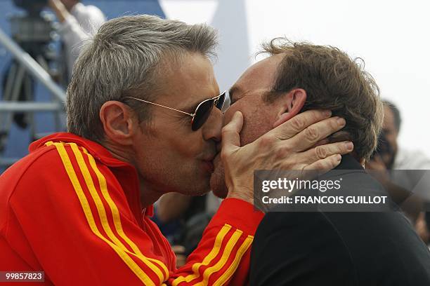 French actor Lambert Wilson kisses French director Xavier Beauvois as they pose during the photocall of "Des Hommes et des Dieux" presented in...