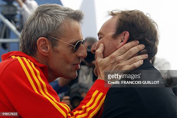 French actor Lambert Wilson kisses French director Xavier Beauvois as they pose during the photocall of "Des Hommes et des Dieux" presented in...