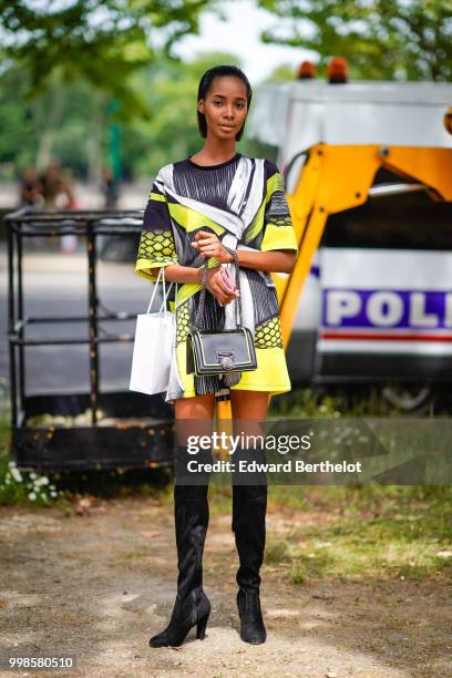 Model wears a yellow and black dress, black thigh high boots, a Chanel bag, outside Balmain, during Paris Fashion Week - Menswear Spring-Summer 2019,...