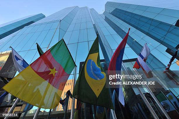 People walk pass a building as they go to work in Johannesburg on May 17, 2010 with the flags of the 32 countries competing in the Fifa World Cup...