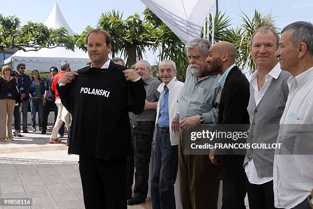 French director Xavier Beauvois poses with a tee-shirt in support of Franco-Polish director Roman Polanski during the photocall of "Des Hommes et des...