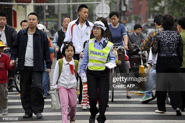 Chinese policewoman helps a schoolgirl cross a street as part of a new security beat outside an elementary school in Beijing on May 18, 2010. Five...
