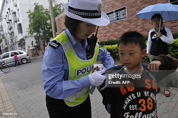 Chinese policewoman helps a schoolboy with his bag as part of a new security beat outside an elementary school in Beijing on May 18, 2010. Five...