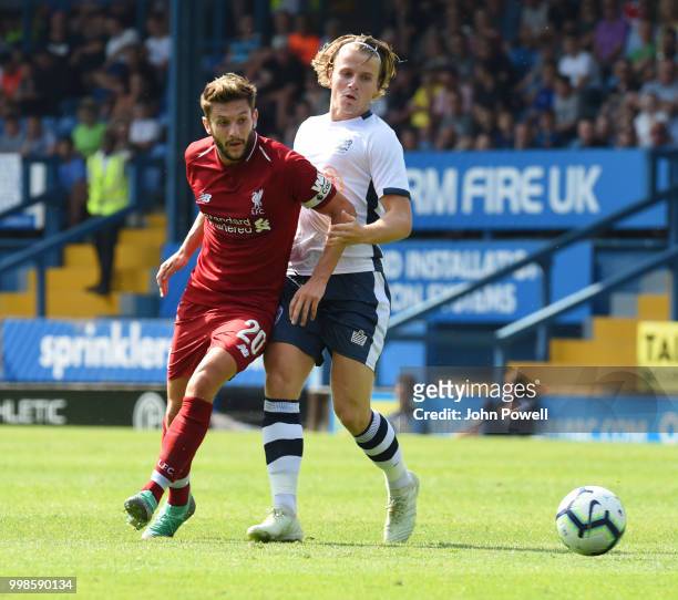 Adam Lallana of Liverpool competes with Tom Whelan of Bury during the Pre-Season friendly match between Bury and Liverpool at Gigg Lane on July 14,...