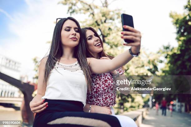 weibliches paar nimmt selfie weile entspannen im stadtpark - aleksandar georgiev stock-fotos und bilder