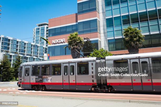San Francisco Municipal Railroad train passing by the headquarters of pharmaceutical company Nektar in the Mission Bay neighborhood of San Francisco,...