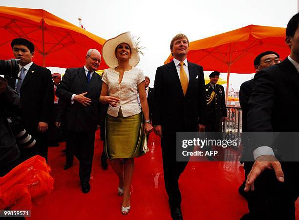 Dutch Prince Willem-Alexander waves to the cheering crowd as he and Princess Maxima arrive at the World Expo Centre in Shanghai on May 18 where they...