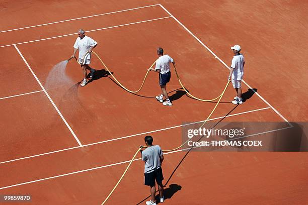 People spray water on the tennis clay-court, 19 May 2004 at Roland-Garros in Paris, before this season's second Grand Slam tournament starting at...