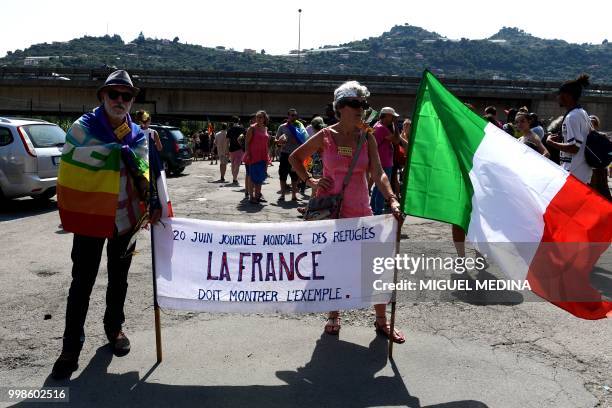 Two persons hold a banner reading " World refugee day, France must show the example" during a demonstration at the call of an Italian association...