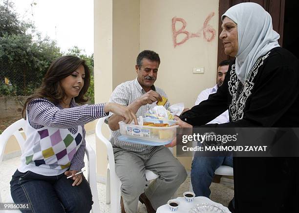 Afifa Fakih aunt of Rima Fakih, a Lebanese-American who won the Miss USA pageant, gives sweets to relatives at the latter's native village of Srifa...