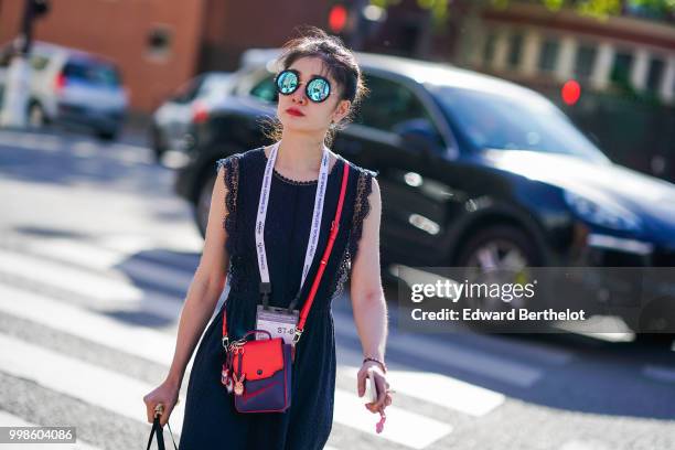 Guest wears round mirror sunglasses, a black sleeveless lace dress, a blue and red bag, outside Dries Van Noten, during Paris Fashion Week - Menswear...