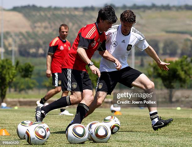 Head coach Joachim Loew of Germany runs for the ball with Arne Friedrich during the German National Team training session at Verdura Golf and Spa...