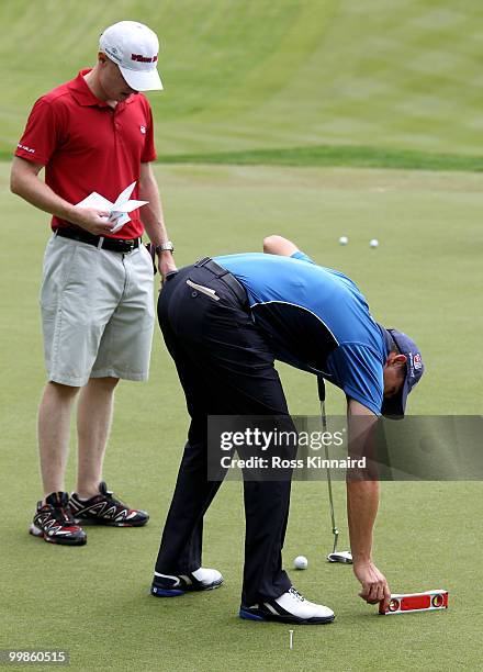 Padraig Harrington of Ireland checks the level of a green with caddy Ronan Flood during a practice round at Wentworth prior to the BMW PGA...