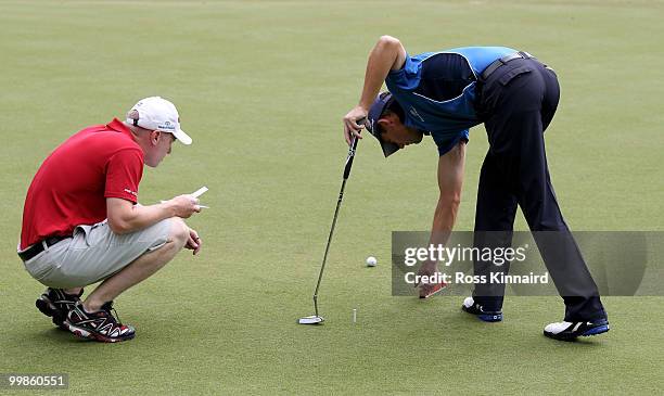 Padraig Harrington of Ireland checks the level of a green with caddy Ronan Flood during a practice round at Wentworth prior to the BMW PGA...