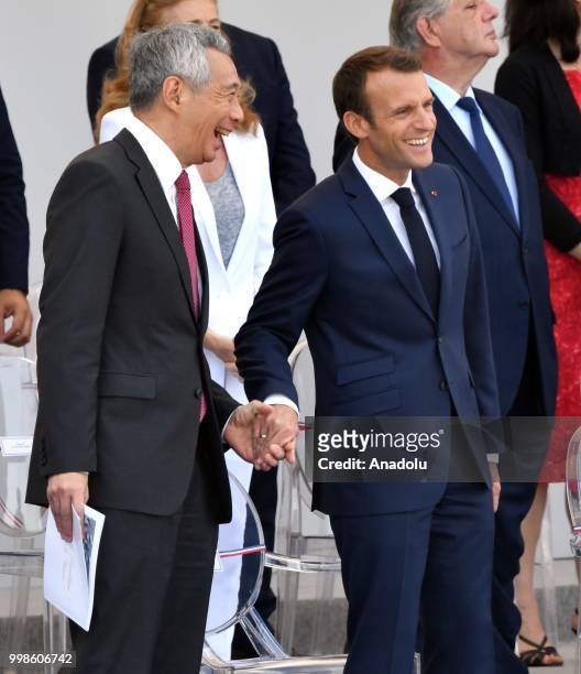 French President Emmanuel Macron and Singapore Prime Minister Lee Hsien Loong speaks during the annual Bastille Day military parade at the Place de...