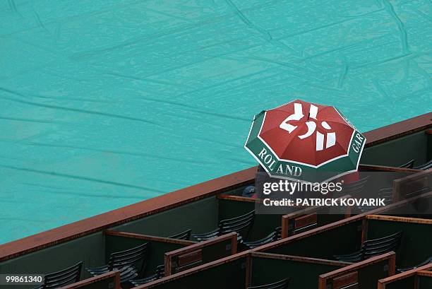 Visitors wait as it rains during the first round of the French Tennis Open, at Roland Garros, in Paris, on May 26, 2008. AFP PHOTO/ PATRICK KOVARIK