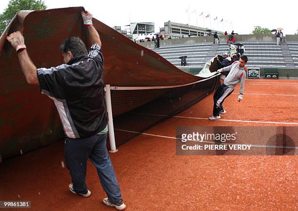 Maintenance workers cover the court N°3 as the match between French Julien Benneteau and US Vincent Spadea is interrupted due to rainy weather on the...