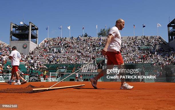 Court attendents bag the court ahead of play between Hungary's Agnes Szavay and Slovakia's Dominika Cibulkova during a French Open tennis round of 16...