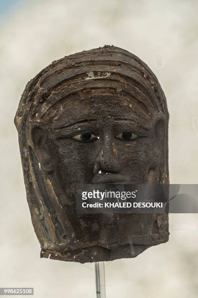 Picture taken on July 14, 2018 shows a gilded silver mummy mask found on the face of the mummy of the second priest of Mut on display in front of the...