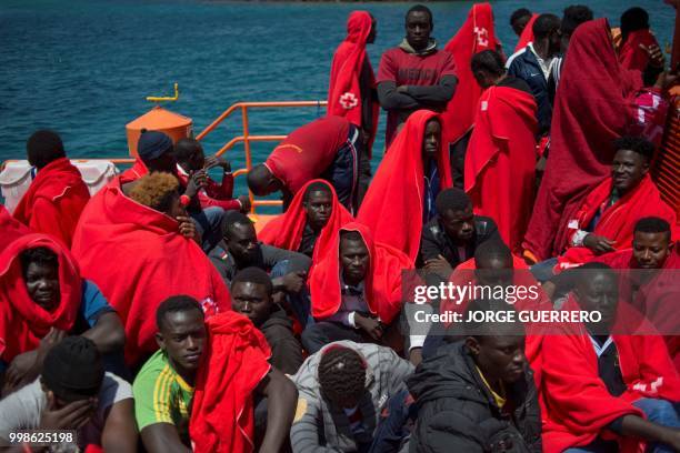 Migrants keep warm wrapped in Red Cross blankets after arriving aboard a coast guard boat at Tarifa's harbour on July 14, 2018. - Spanish rescuers...