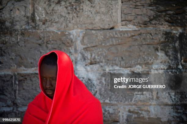 Migrant keeps warm wrapped in Red Cross blankets after arriving aboard a coast guard boat at Tarifa's harbour on July 14, 2018. - Spanish rescuers...