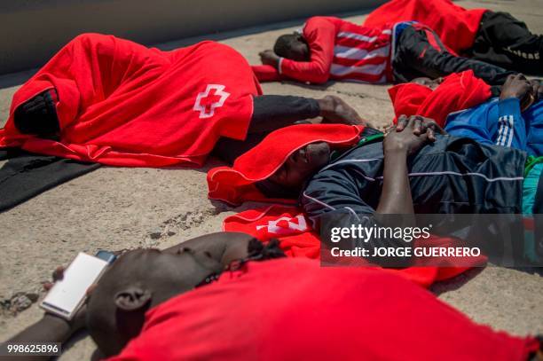 Migrants keep warm wrapped in Red Cross blankets after arriving aboard a coast guard boat at Tarifa's harbour on July 14, 2018. - Spanish rescuers...