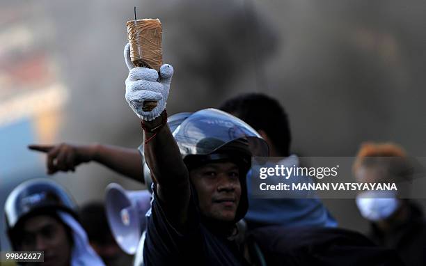 Red Shirt anti-government protester holds a molotov cocktail as he prepares to throw it towards security forces on the Rama 4 road in Bangkok on May...