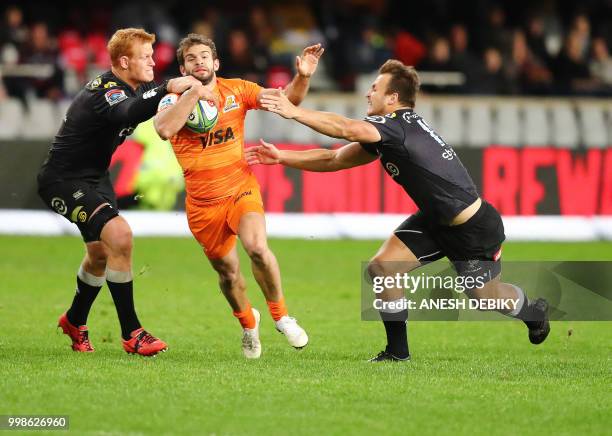 Jaguares' fullback Ramiro Moynao is tackled by Sharks' loose forward Philip van der Walt and center Andre Esterhuizen during the Super Rugby match...