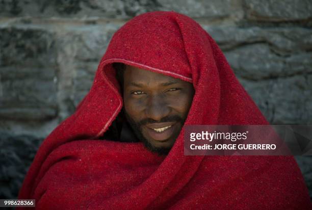Migrant keeps warm wrapped in Red Cross blankets after arriving aboard a coast guard boat at Tarifa's harbour on July 14, 2018. - Spanish rescuers...