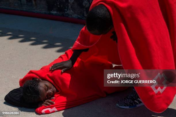 Migrants keep warm wrapped in Red Cross blankets after arriving aboard a coast guard boat at Tarifa's harbour on July 14, 2018. - Spanish rescuers...