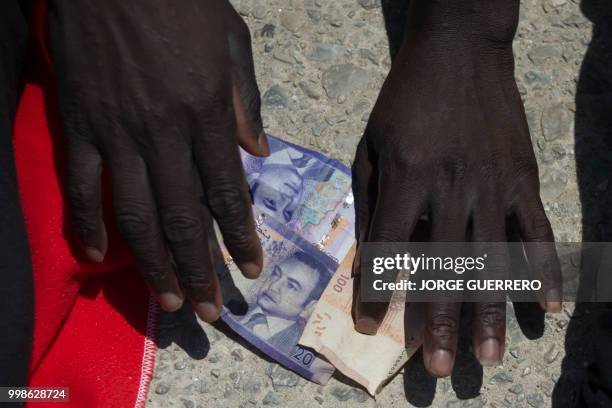 Migrant counts money after arriving aboard a coast guard boat at Tarifa's harbour on July 14, 2018. - Spanish rescuers saved more than 340 migrants...