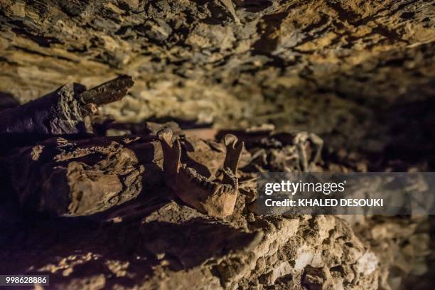 Picture taken on July 14, 2018 shows remains of mummies inside a burial chamber, in the Saqqara necropolis, south of the Egyptian capital Cairo on...