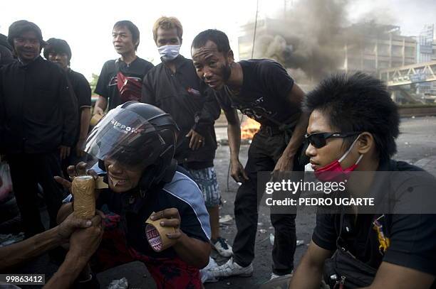 Thai demonstrator uses his teeth to cut tape as he makes a molotov cocktail behind a barricade in downtown Bangkok on May 18, 2010. Thousands of...