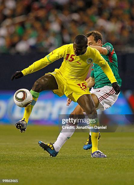 Mame Saher of Senegal tries to control the ball under pressure from Gerardo Torrado of Mexico during an international friendly at Soldier Field on...