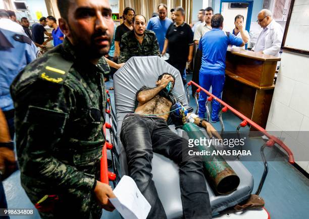 Graphic content / Members of Hamas' military police bring in an Palestinian injured by Israeli air strikes to receive medical attention at al-Shifa...