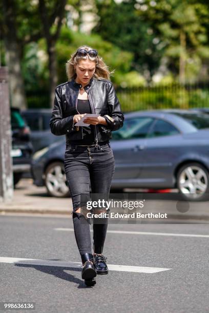 Guest wears sunglasses, a black leather jacket, ripepd jeans, outside Lanvin, during Paris Fashion Week - Menswear Spring-Summer 2019, on June 24,...