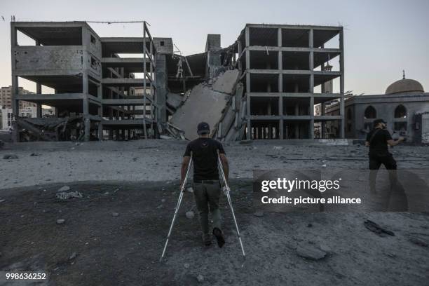 Palestinians stand at the site where a building was damaged by an Israeli air strike in Gaza City, Gaza Strip, 14 July 2018. Israel's military...