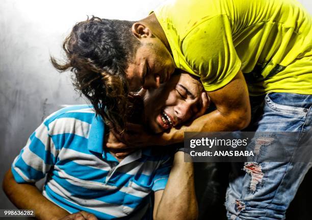 Palestinian youths mourn at al-Shifa hospital morgue on July 14, 2018 after two teenagers were killed in one of a series of Israeli raids. - Aged 15...