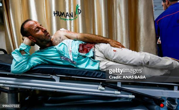 Graphic content / A Palestinian injured by Israeli air strikes lies on a gurney after receiving treatment at al-Shifa hospital in Gaza City on July...