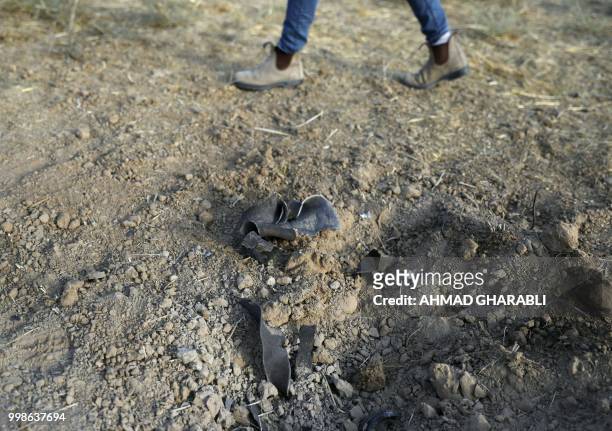Resident of the southern Israeli city of Sderot walks near pieces of shrapnel and a crater caused by a rocket reportedly fired from the Gaza Strip on...