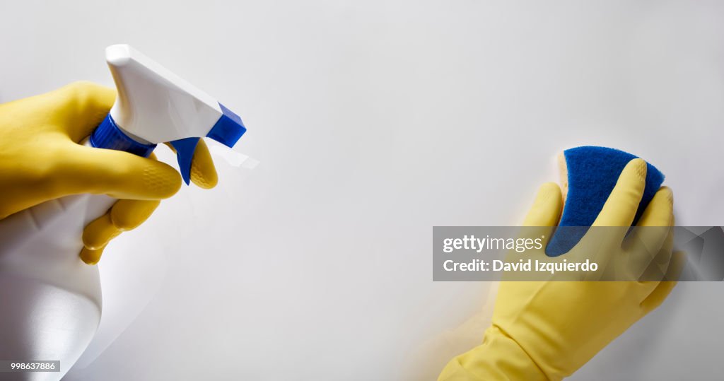 Hands of cleaning staff with scourer and sprayer working