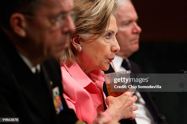 Secretary of State Hillary Clinton sips iced tea while testifying before the Senate Foreign Relations Committee with Defense Secretary Robert Gates...
