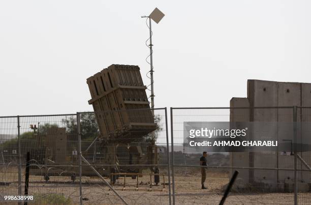 An Israeli soldier stands next to an Iron Dome defence system, designed to intercept and destroy incoming short-range rockets and artillery shells,...