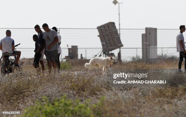 Israelis stand next to an Iron Dome defence system, designed to intercept and destroy incoming short-range rockets and artillery shells, near the...