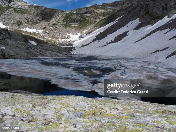 partly frozen upper paione lake (lago del paione superiore), bognanco valley - lepontinische alpen stock-fotos und bilder