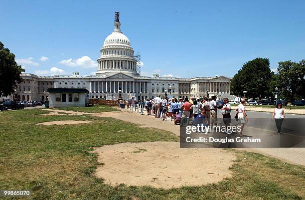 Tourist stand in line on the East Front of the U.S. Capitol waiting for a tour of the historic building. The area that is to be used as a underground...