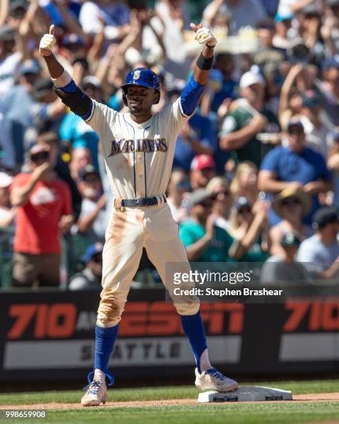 Dee Gordon of the Seattle Mariners gestures to the dugout after hitting a double and advancing to third base on a throwing error during a game...